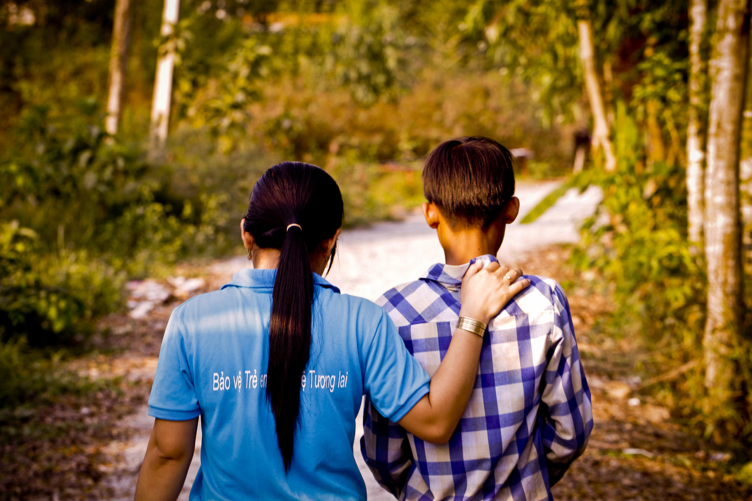 Backs of adolescent boy and girl with hand on one shoulder