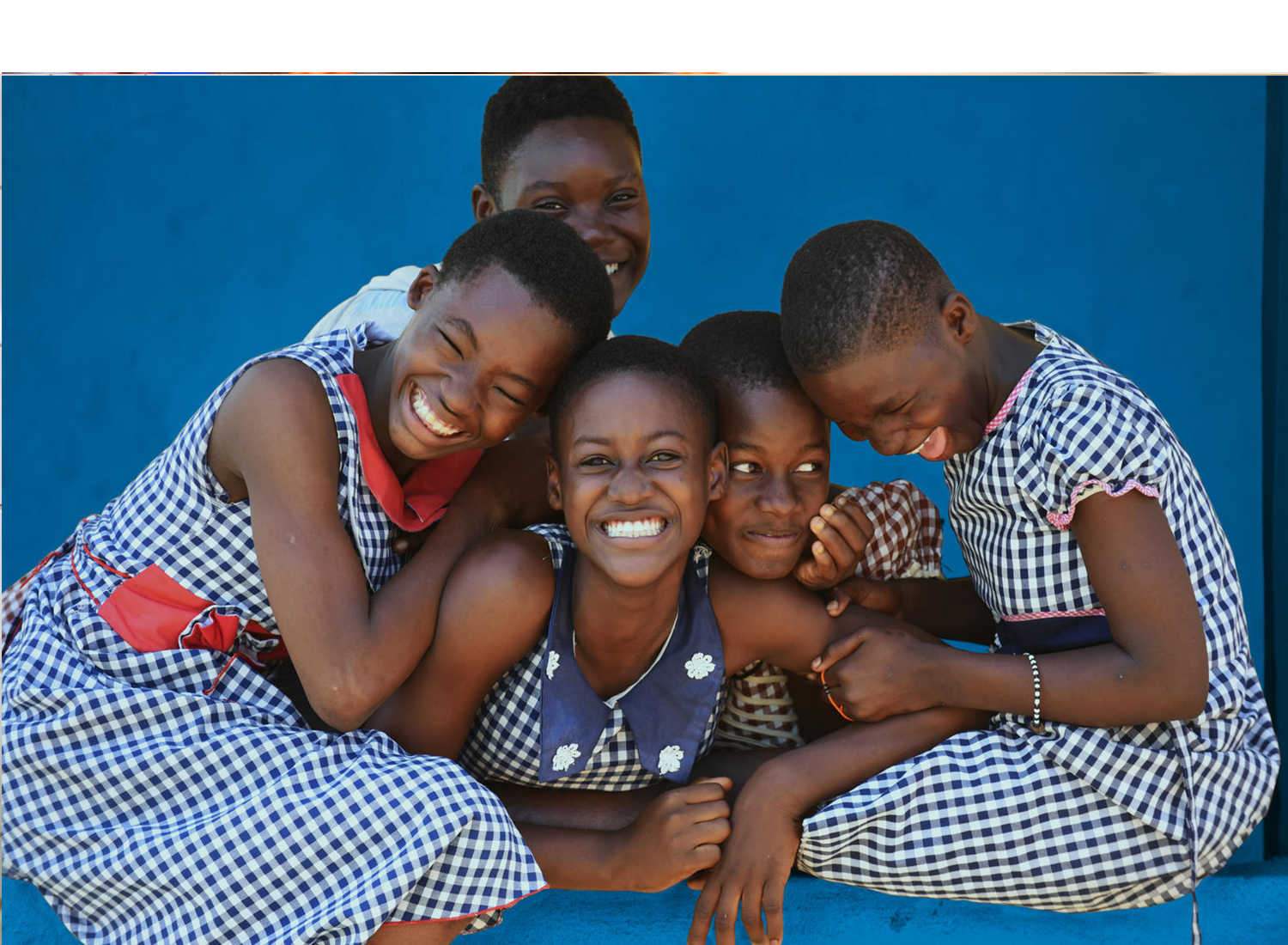 five young girls in leaning on each other, laughing and smiling.