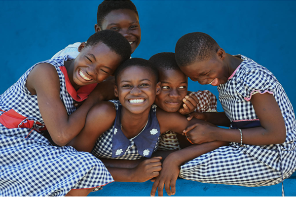 five young girls leaning on each other, laughing and smiling
