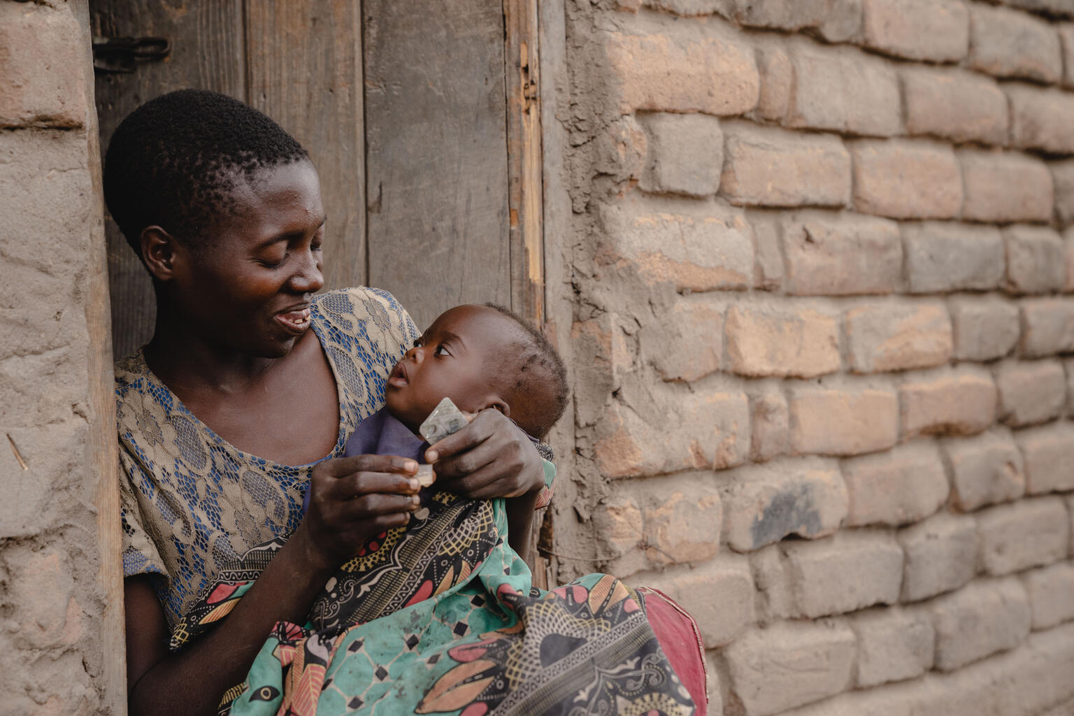 A mother prepares to adminster medicine to her infant