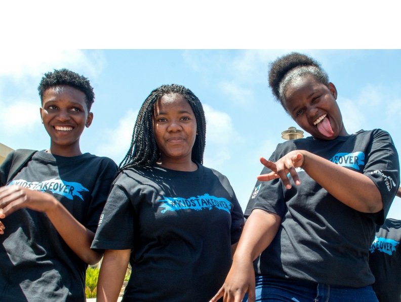 Three young girls looking happy and wearing a t-shirt that reads #kidstakeover