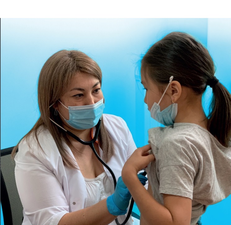Healthcare professional wearing a mask auscultates young girl