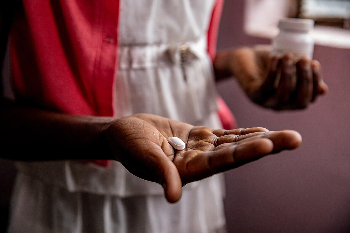 A close up of a grandmothr's hand holding out a pill for her granddaughter