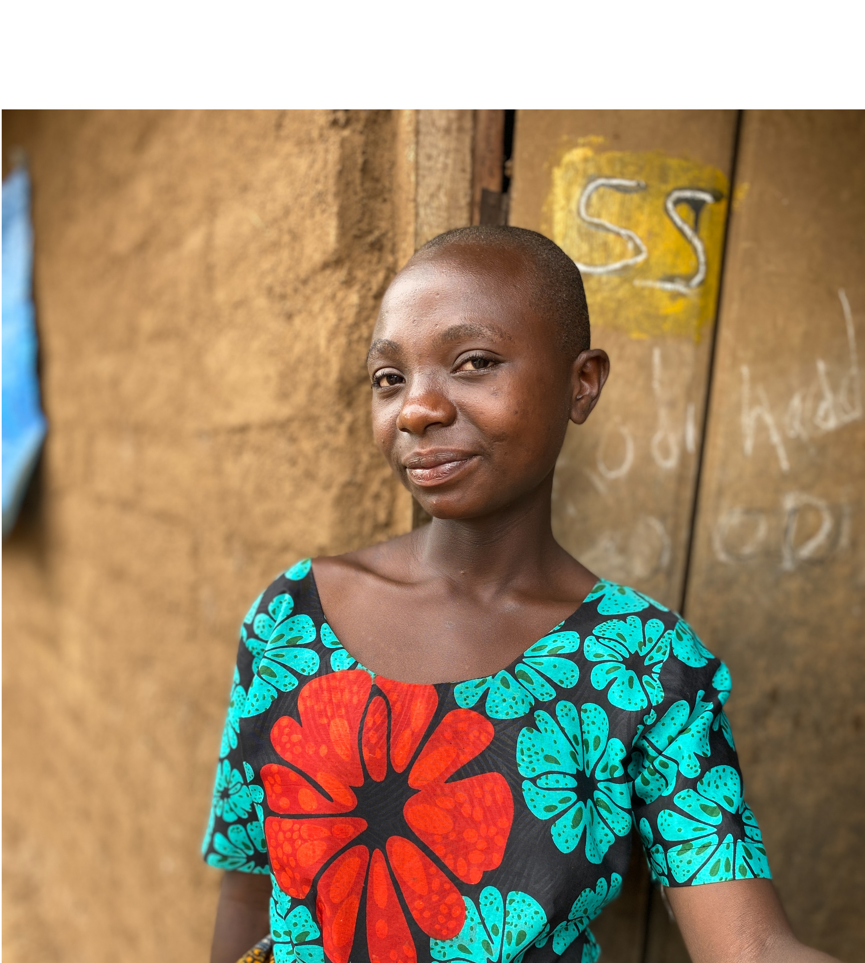 Twelve-year-old girl stands in front of her home in Tanzania.