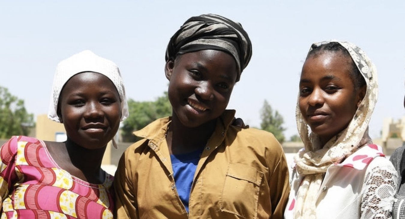 Three young women arm in arm and smiling